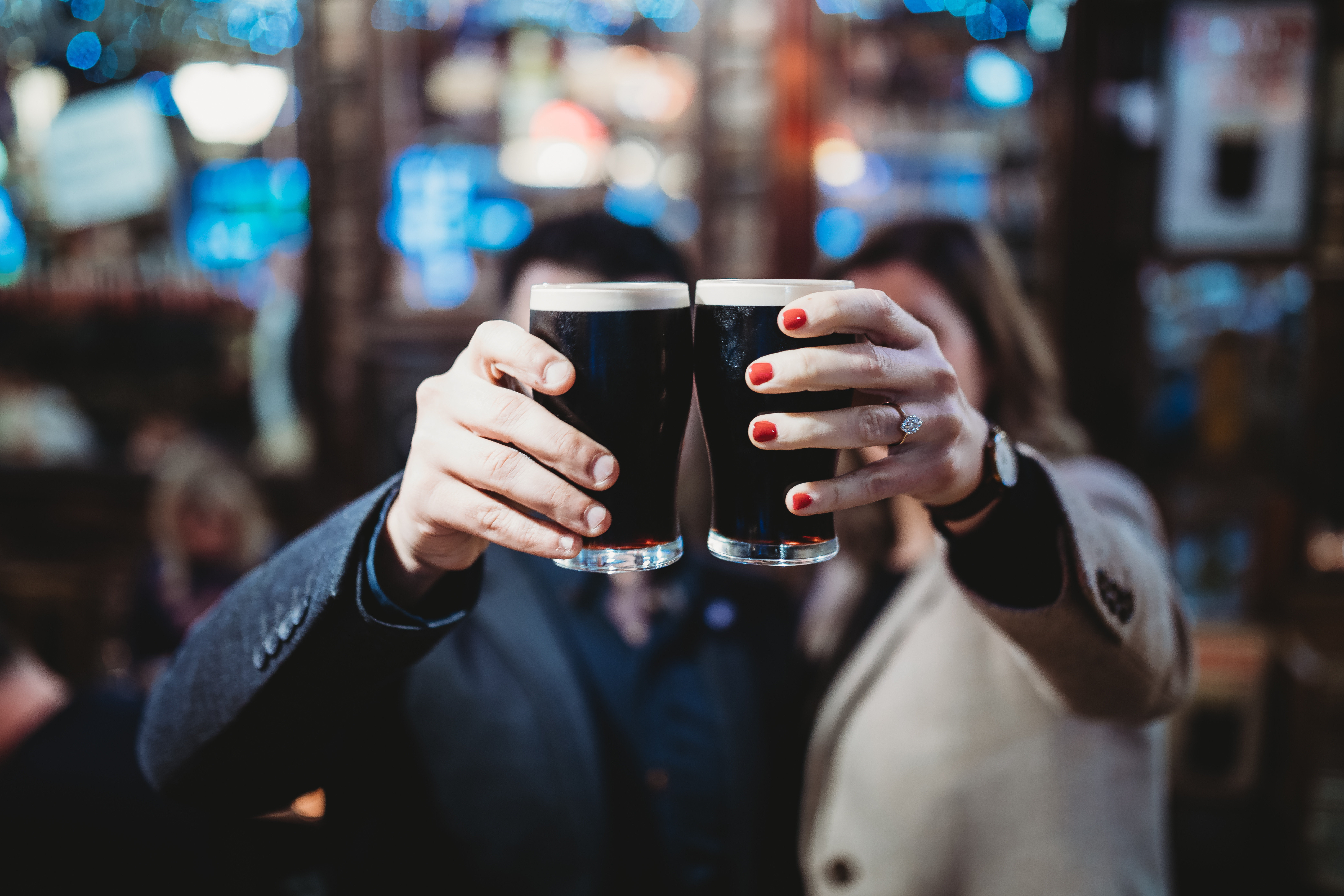 Two people cheering Guiness glasses