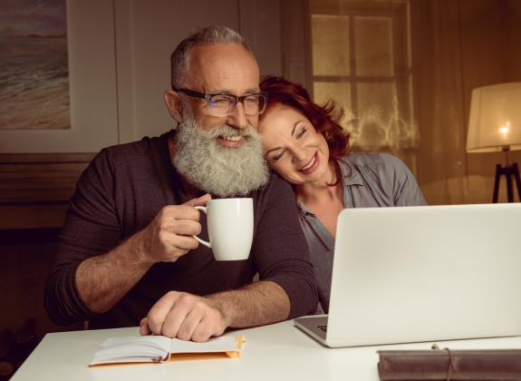portrait of husband and wife sitting at the table and using laptop at home