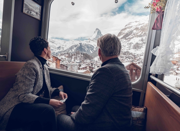 a couple sitting in nostalchic class onboard the gornergrat looking out the window in winter