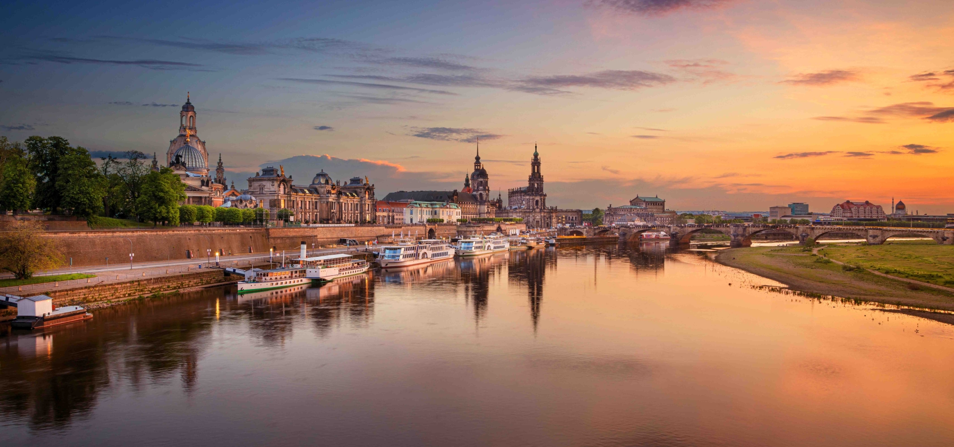 Panoramic cityscape image of Dresden, Germany with reflection of the city in the Elbe river, during sunset.