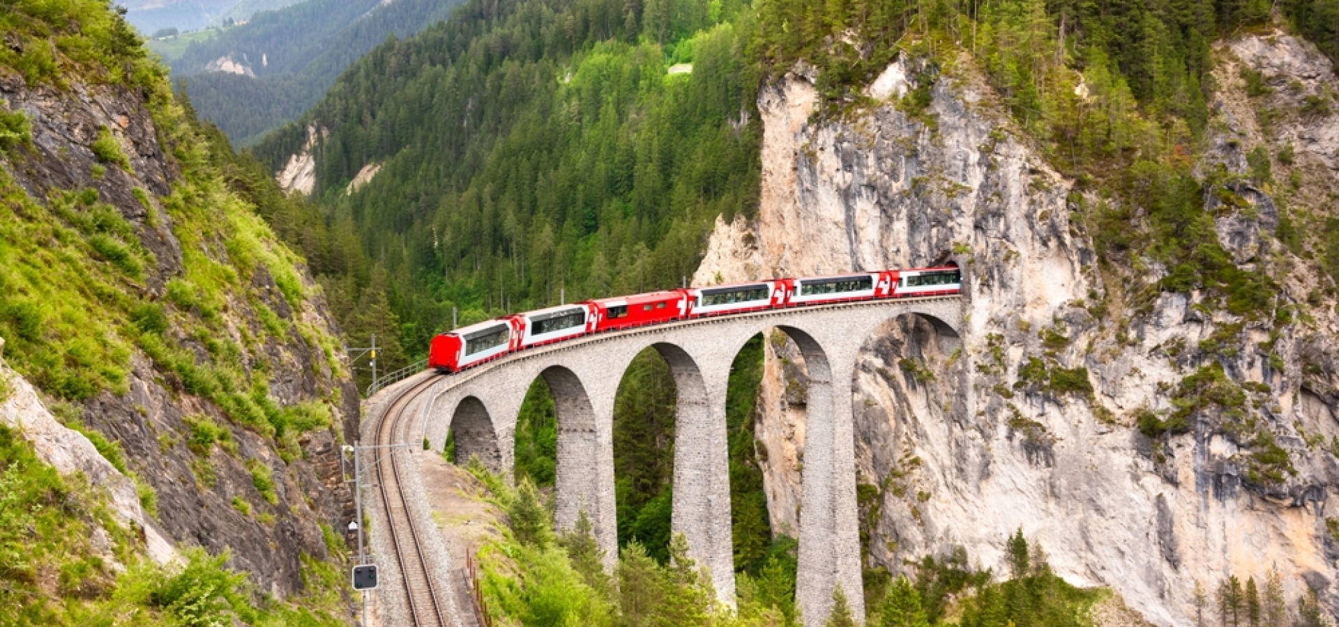 Swiss red train on viaduct in mountain, scenic ride