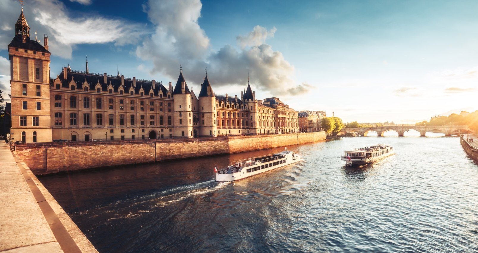 Dramatic sunset over river Seine and Conciergerie in Paris, France, with cruise boats and Pont Neuf. Colourful travel background. Romantic cityscape.
